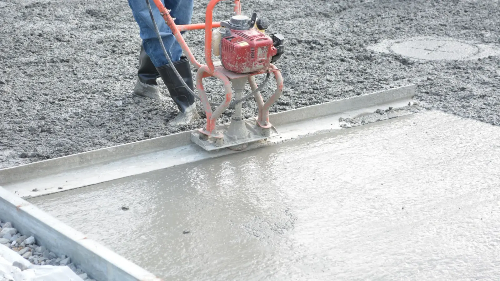 Power screed levelling a freshly poured concrete slab on a residential job