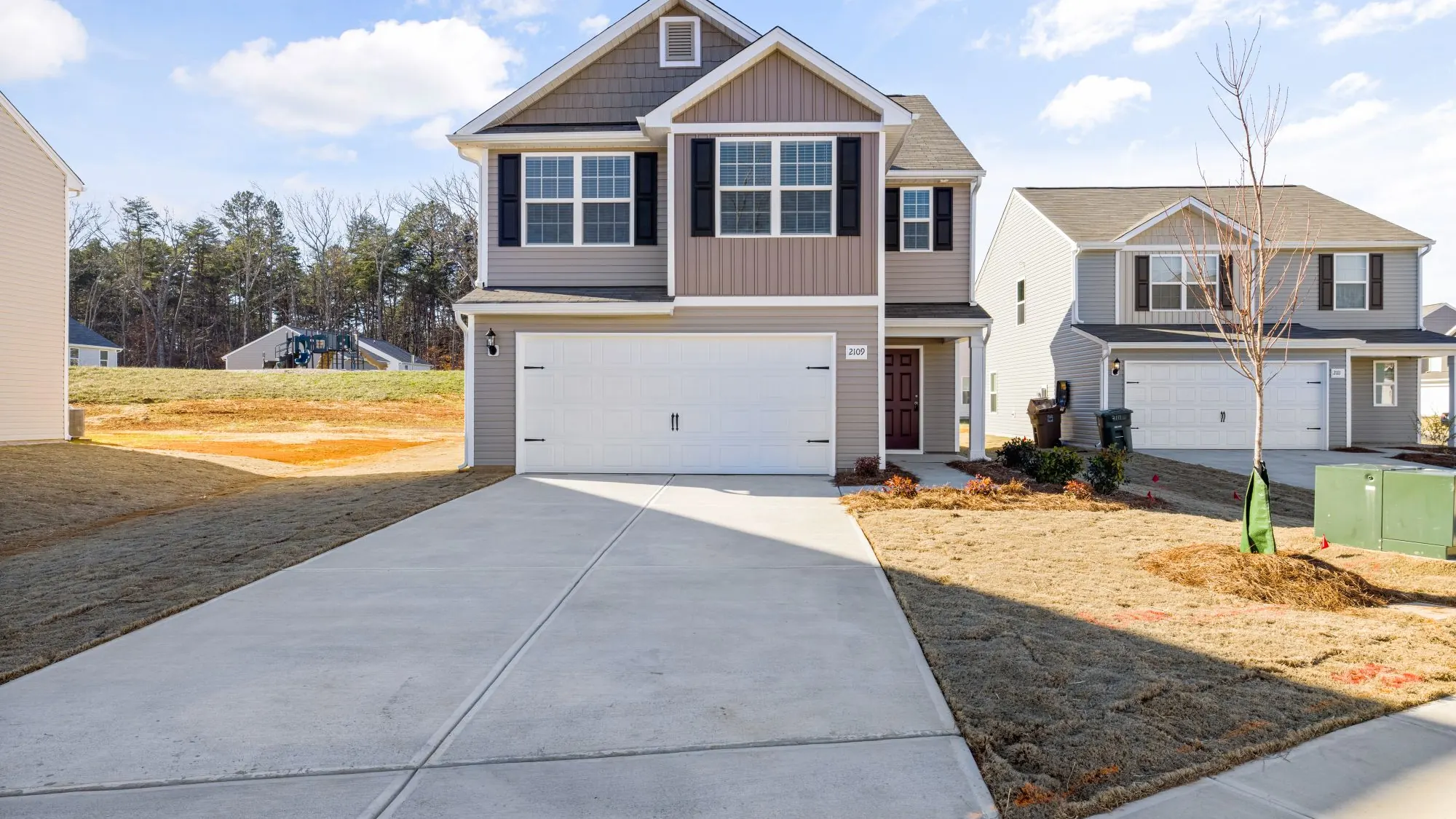Newly built suburban house with a broad concrete driveway and front walk