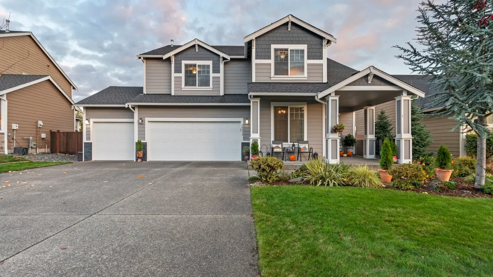 Two-storey suburban home with a wide concrete driveway at dusk