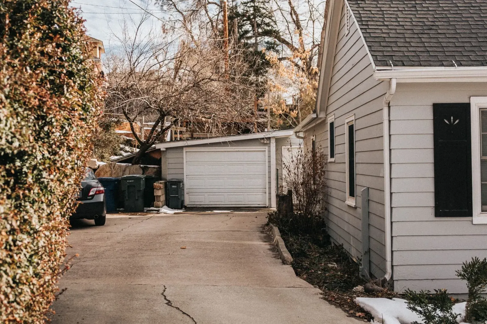 Aging residential concrete driveway running to a detached garage, cracked and ready for replacement