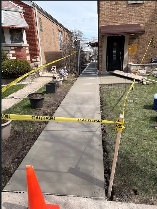 Freshly poured concrete front walkway and porch pad between two brick homes